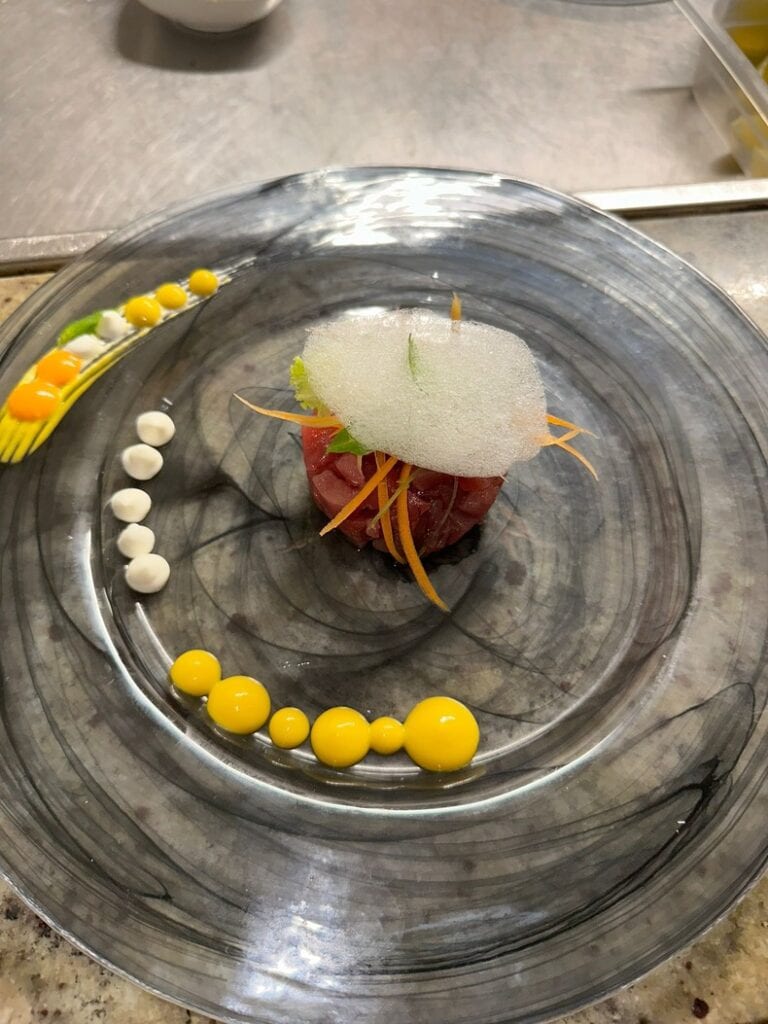 Gourmet dish with tuna tartare and colorful sauce decorations.