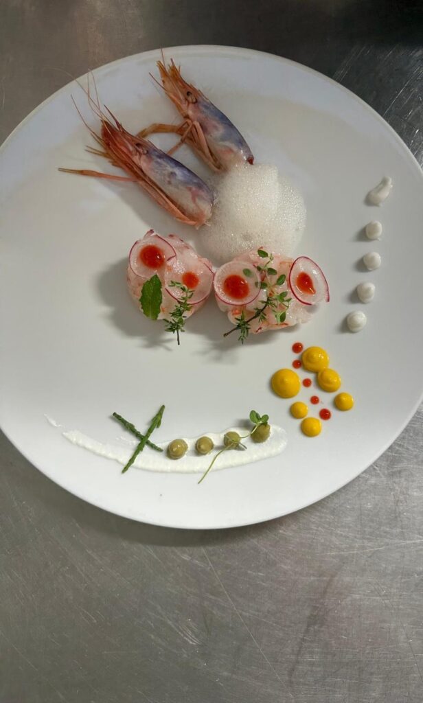 Gourmet dish with shrimp, foam and colorful sauce decorations.