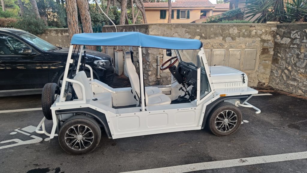White electric car parked on street, side view.