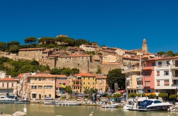 Panoramic view of Castiglione della Pescaia with harbor and colorful houses.
