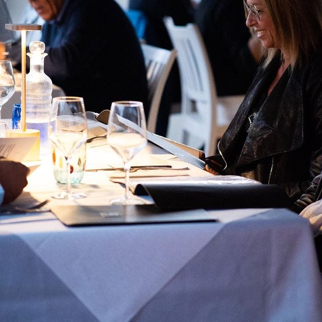 People dining in an elegant restaurant, white tablecloths.