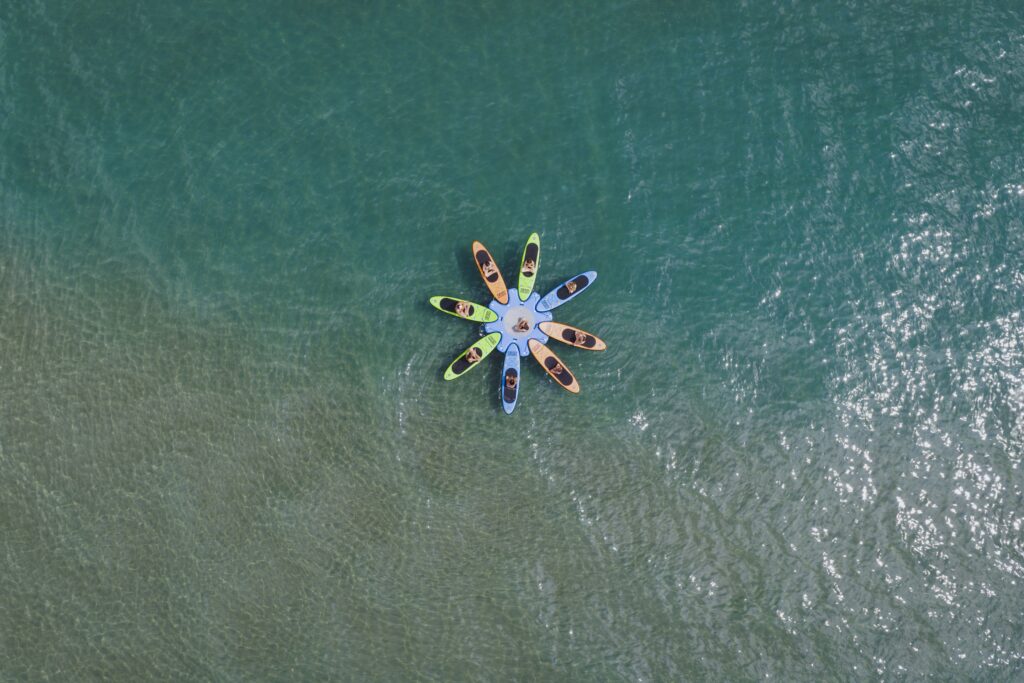 Yoga SUP al Bagno Le Cannucce. Vista aerea di persone che fanno yoga su tavole SUP in mare.